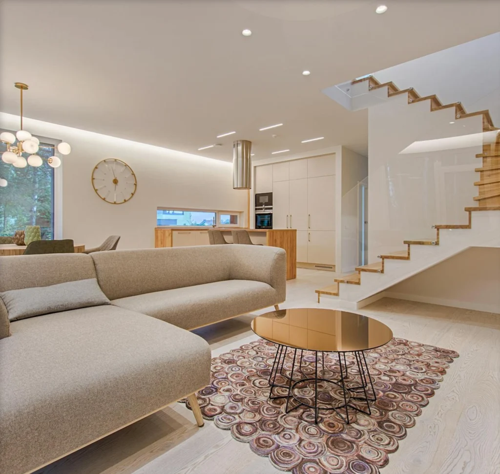 Intérieur moderne d'une maison avec salon, cuisine ouverte et escalier design. Ambiance lumineuse et matériaux haut de gamme.