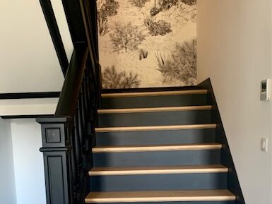 Escalier moderne avec marches en bois, paroi décorée d'un papier peint naturel. Atmosphère chaleureuse et élégante.