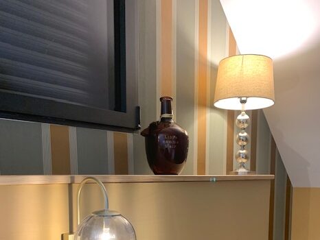 Objet décoratif sur une étagère avec une lampe et une bouteille, dans une pièce au style moderne et élégant.