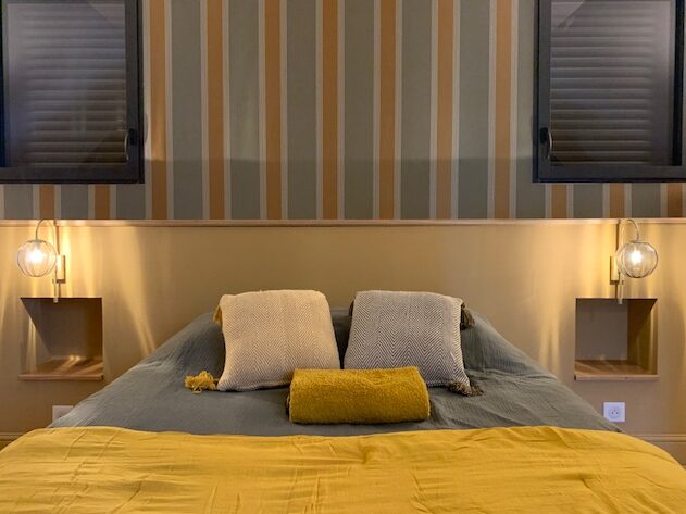 Chambre moderne avec un lit confortable, décoration élégante et éclairage chaleureux. Style raffiné et ambiance accueillante.