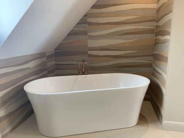Baignoire moderne en îlot dans une salle de bain élégante avec mur en carrelage texturé.