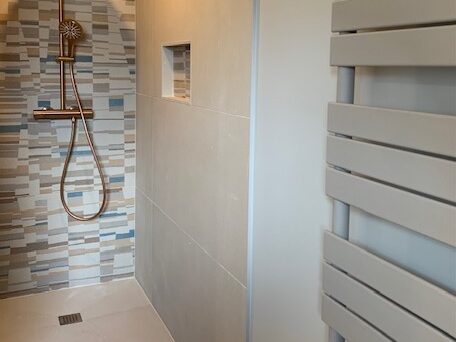 Salle de bain moderne avec douche design et carrelage en mosaïque, intégrant des équipements de qualité.