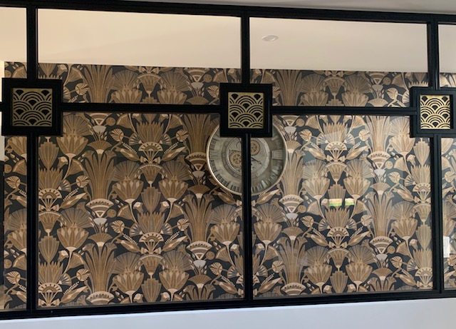 Mur décoratif avec motif floral en relief et horloge au centre, mettant en valeur un intérieur moderne et élégant.