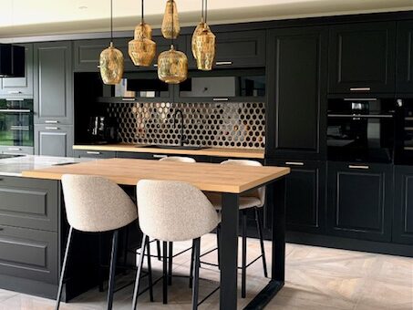 Cuisine moderne et élégante avec des éléments en noir et bois, éclairage design et sièges confortables.