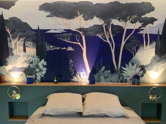 Chambre moderne avec mur décoratif de paysages forestiers et lit à deux places, éclairage doux.
